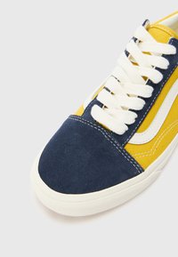 Blue and yellow sneaker with canvas and suede materials; features white laces, white side accents, and contrast stitching details.