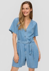 Salopette en denim bleu clair avec des manches courtes, un col en V, des boutons à l'avant, une ceinture à nouer ajustable à la taille et un short ample.