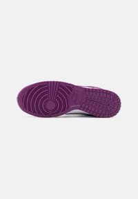 Sola de um sneaker Nike em borracha roxa, apresentando padrões de piso circulares e retangulares, com a marca na área do calcanhar.