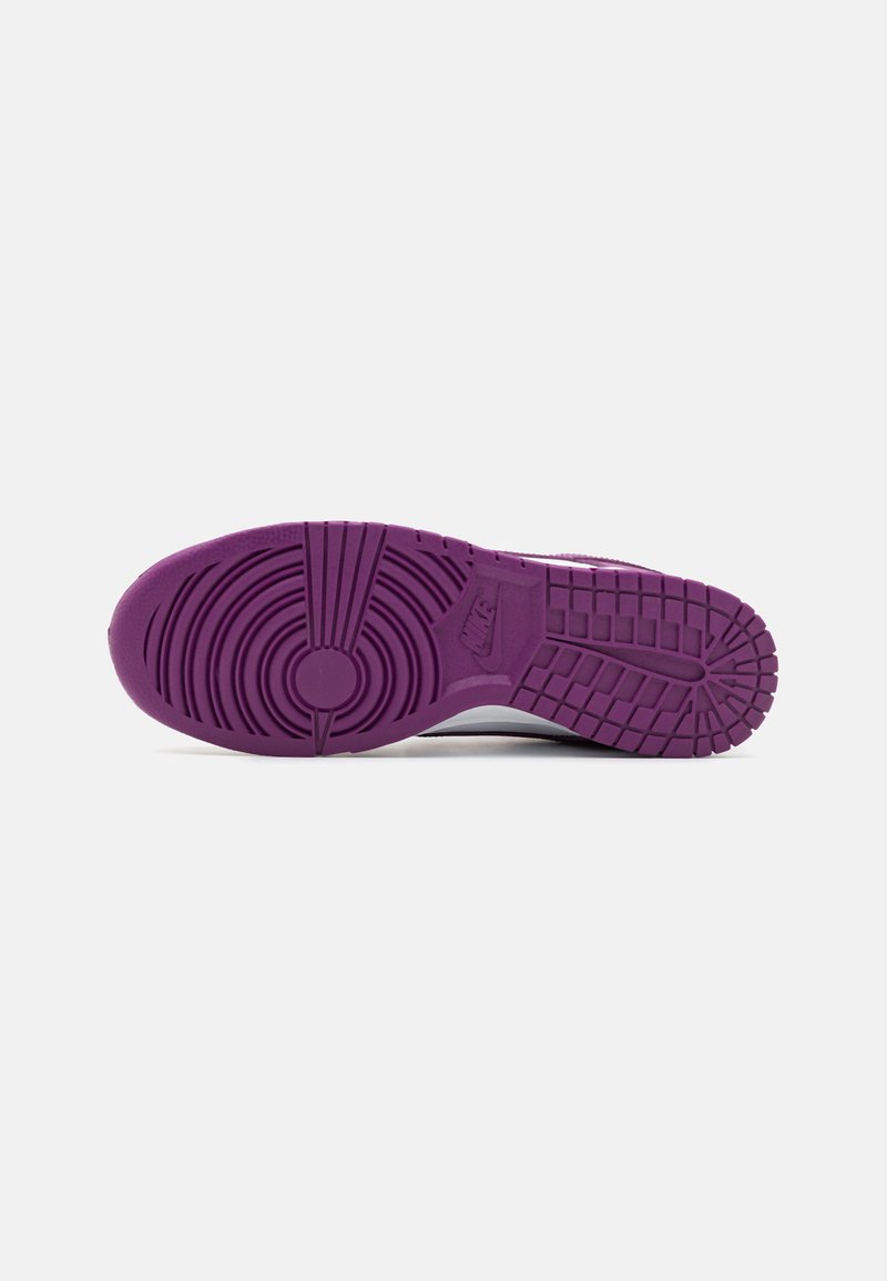 Suela de zapatilla Nike en goma púrpura, con patrones de tracción circulares y rectangulares, y con la marca en el área del talón.
