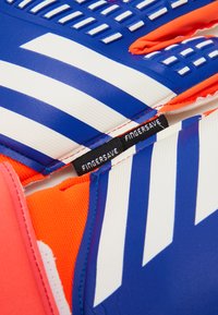 Guanti da portiere blu e bianchi con superficie texturizzata, accenti arancioni e un'etichetta "Fingersave" vicino all'area del polso.