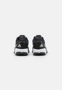 Black athletic shoes with a textured mesh upper and padded collar, featuring white accents and the Adidas logo on the heel.