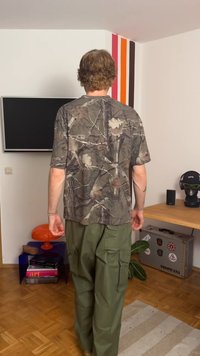 Πουκάμισο με καμουφλάζ σε αποχρώσεις πράσινου και καφέ, συνδυασμένο με χαλαρές cargo παντελόνες σε ελιά. Καθημερινή εφαρμογή, πρακτικός σχεδιασμός.