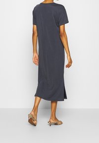 Abito grigio antracite lungo fino alla caviglia con maniche corte, fessure laterali e vestibilità rilassata, realizzato in un tessuto morbido e leggero.