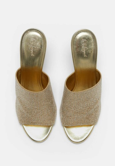 Sandales ouvertes à talons plats en or avec larges brides recouvertes de strass scintillants et semelles métalliques dorées.