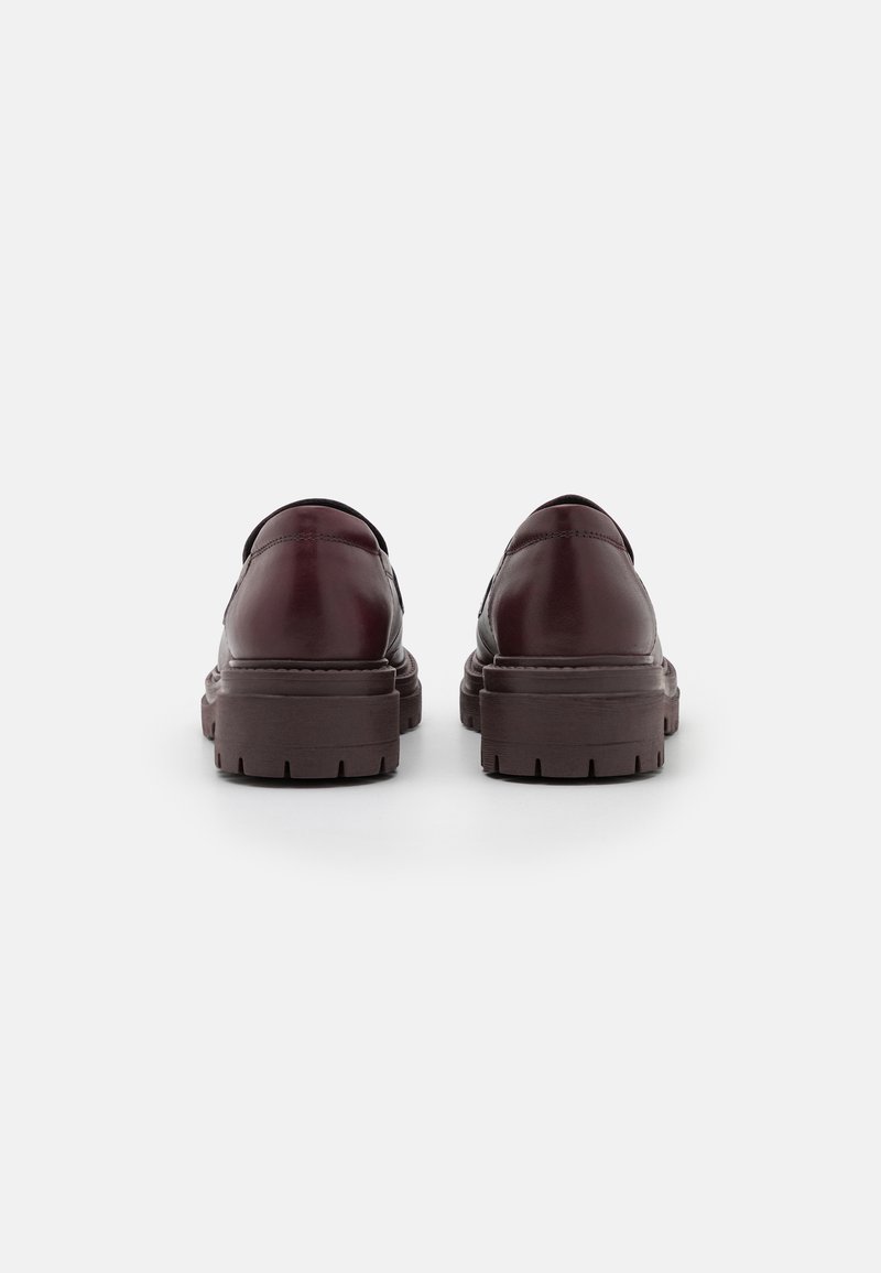 Bordeaux leren schoenen met een strak ontwerp, voorzien van een stevige bruine zool met diepe noppen en ronde hakken, zichtbare stiksels.