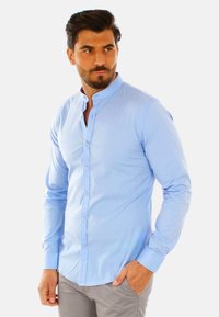 Camicia a maniche lunghe azzurro chiaro con colletto a bandino e patta dei bottoni, caratterizzata da una superficie liscia e un design aderente.