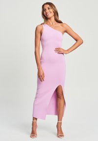 Asymmetriska klänning med en axel i ljusrosa, tillverkad av figurnära, ribbat material. Har ett lårhögt slits på ena sidan.