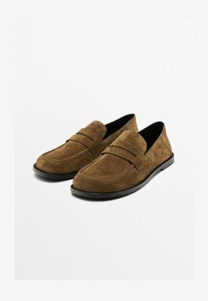 Bruna mockaläders loafers med låg profil, med en sydd detalj över vampen och en svart gummisula. Slät textur, minimalistisk design.