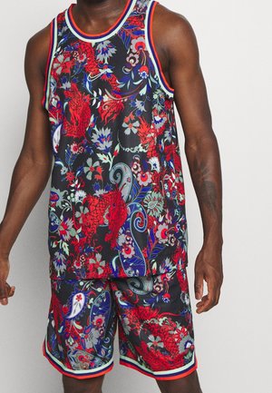 Mand iført matchende basketballtrøje og shorts med dristigt rødt, blåt og gråt blomster- og dragemønster på sort baggrund.