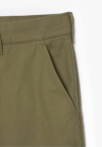 Olijfgroene broek met een zachte, gestructureerde stof, gestikte naden en een zijzakdetail.