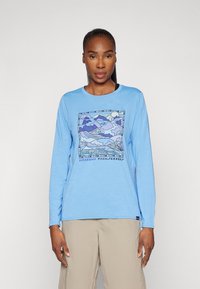 Long-sleeve blue T-shirt featuring a graphic landscape print in shades of purple and blue, with "Patagonia Trailseekers" text at the bottom.