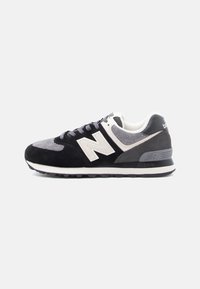Čierne, sivé a biele tenisky New Balance so semišovými a sieťovinovými panelmi, bielym logom "N" a textúrovanou gumovou podrážkou.