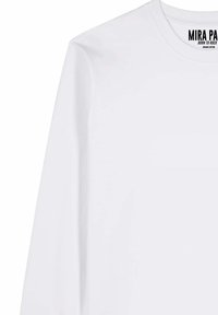 Maglietta bianca a maniche lunghe realizzata in cotone biologico, con scollo a girocollo e l'etichetta "MIRA PA" stampata in nero sul colletto.
