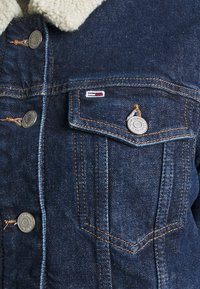 Denim jacket with fleece collar, buttoned chest pocket, and metal buttons embossed with "Tommy Jeans New York."