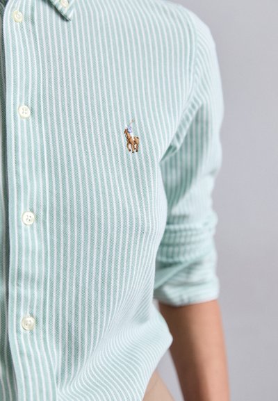 Camicia a righe verde chiaro con colletto con bottoni, caratterizzata da un piccolo logo ricamato di un giocatore di polo sul lato sinistro del petto.