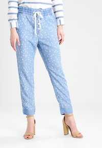 Himmelblaue Jogginghosen mit einem Kordelzugbund, dekorativem Knopfschluss und weißen Vogelmustern überall. Aus weichem, leichtem Stoff.