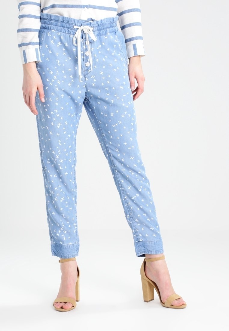 Himmelblaue Jogginghosen mit einem Kordelzugbund, dekorativem Knopfschluss und weißen Vogelmustern überall. Aus weichem, leichtem Stoff.