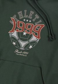 Zielona bluza z kapturem z grafiką piłki nożnej i napisem "ATHLETIC 1999". Posiada sznurki do ściągania i kieszeń z przodu. Miękka tekstura materiału.