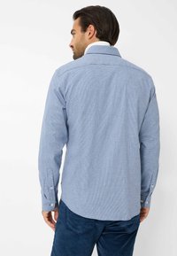 Camicia a quadretti blu con maniche lunghe, colletto e bottoni bianchi, realizzata in un tessuto leggero, con yoke posteriore e orlo curvo.