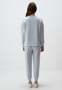 Jasnoniebieska bluza i pasujące dresy wykonane z miękkiego materiału, z luźnym krojem, ściągaczami na mankietach oraz elastycznym pasem. Gładki design, bez wzorów.