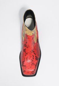 Stivale alla caviglia in finta pelle di serpente rosso e giallo con punta affusolata, superficie testurizzata e suola nera elegante.