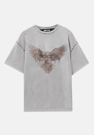 Gray oversized t-shirt with a faded eagle graphic and the text "JUST CAVALLI." Features studs along the sleeve for added detail.