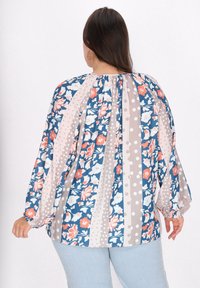 Bluse med blomsterprint, som har blå, pink og grå striber med prikker. Glat stof med samling bagpå og løse ærmer.