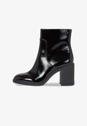 Stivale alla caviglia in pelle verniciata nera con tacco blocco. Caratterizzato da una texture liscia, punta arrotondata e un'apertura laterale. Dettaglio logo discreto.