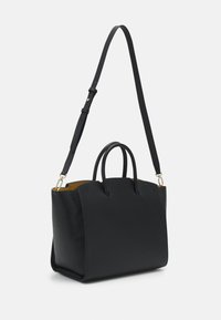 Černá kožená kabelka se strukturovaným tvarem, dvojitými rukojeťmi a odnímatelným popruhem; má hladkou texturu a zlaté kovové prvky.