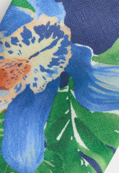 Κοντινό πλάνο υφάσματος με μοτίβο από λουλούδια σε μπλε και μπεζ χρώμα και πράσινα φύλλα πάνω σε υλικό με υφή πλεγμένης ύφανσης.