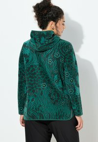 Zielona bluza z kapturem z polaru z wzorem kwiatowym i zwierzęcym, o luźnym kroju i kontrastowymi czarnymi detalami na szwach.