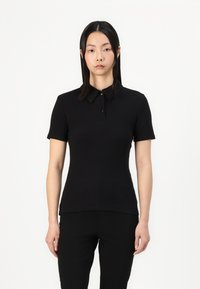 Svart kortärmad pikétröja med krage och knappar, tillverkad av smidig, elastisk tyg, figurnära design med rak nederkant.