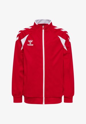 Czerwona sportowa kurtka na pełny zamek z białymi paskami w kształcie szewronów na ramionach, białymi panelami po bokach, ściągaczami na mankietach oraz logo hummel na lewej piersi.