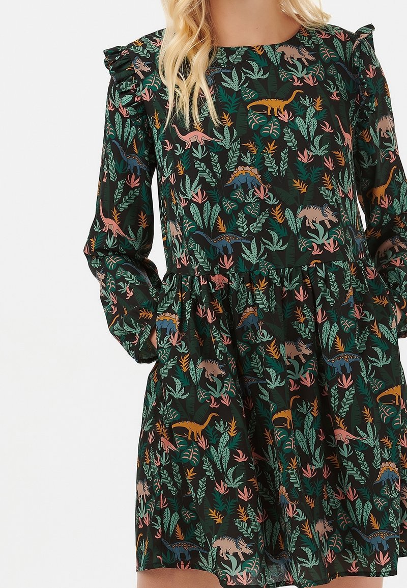 Vestido negro con estampado de flores y dinosaurios, con mangas largas, hombros con volantes y una falda acampanada. Fabricado con tejido ligero.