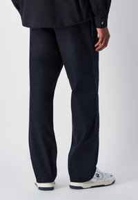 Luźne granatowe spodnie wykonane z bawełny, z bocznymi kieszeniami i prostym krojem. Dobrane z białymi sneakersami.