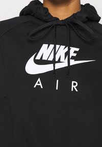 Black hooded sweatshirt made of soft fabric featuring a prominent white Nike logo and "AIR" text, with adjustable drawstrings at the hood.
