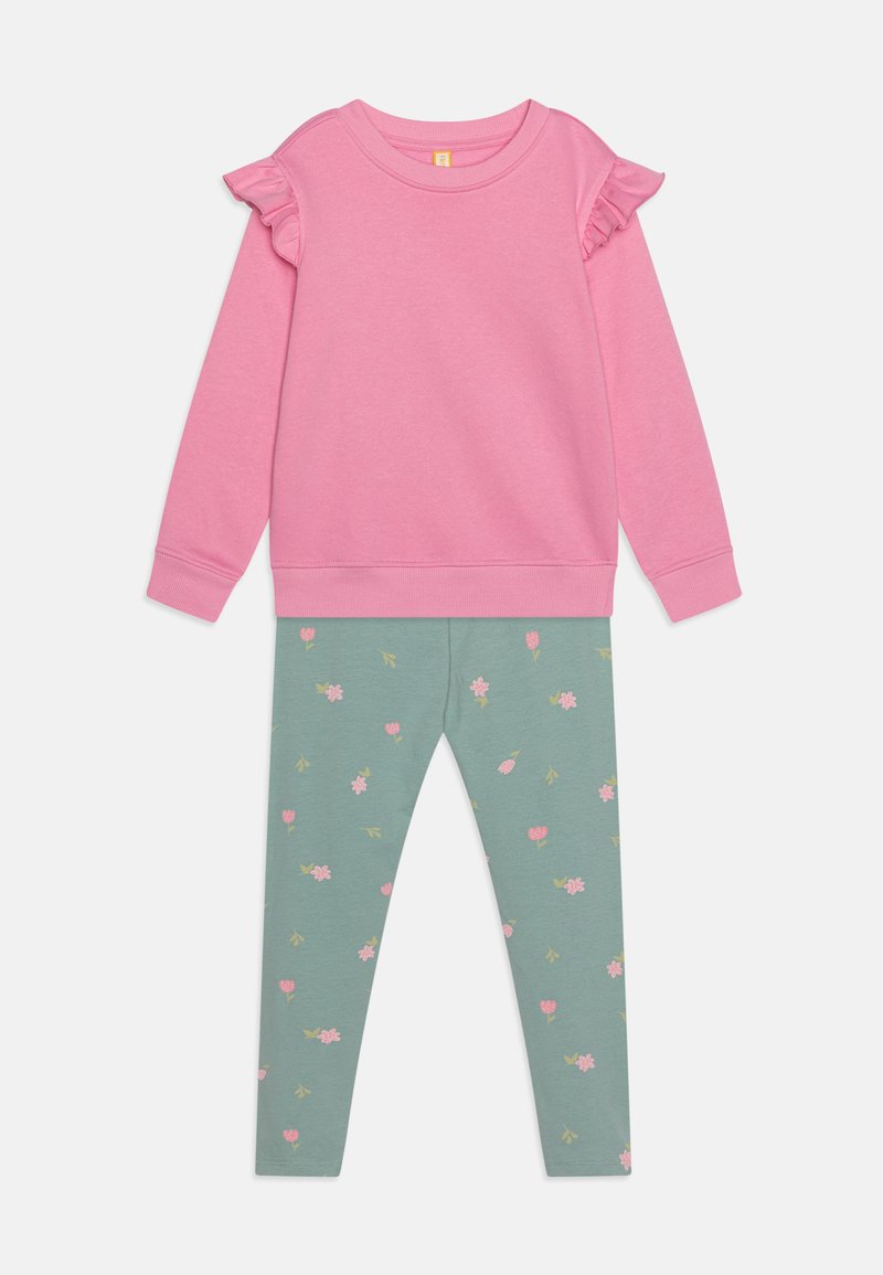 Sudadera de algodón rosa con acentos de volantes en los hombros, combinada con leggings verdes con un patrón floral en rosa y amarillo.