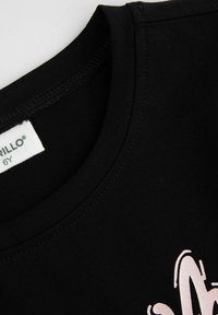 Czarny bawełniany t-shirt z okrągłym dekoltem. Na przodzie znajduje się fakturowany biały nadruk graficzny. Etykieta informuje "6Y" na wytkanym naszywce.