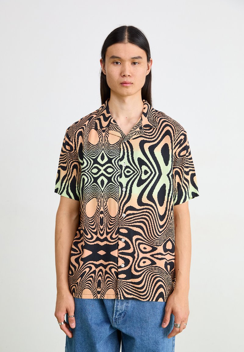 Chemise à manches courtes avec boutons présentant un motif ondulé et abstrait en pêche, vert et noir. Fabriquée en tissu léger avec une coupe décontractée.