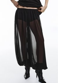 Pantaloni palazzo negri transparenți, cu talie elastică, design fluid și țesătură texturată. Asortați cu pantofi stiletto negri, cu vârf ascuțit.