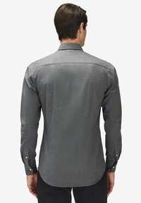 Grå långärmad skjorta med en slät textur, knapplåsningsmanschetter och bakre okdesign. Subtilt mönster synligt i tyget.