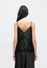 Mustast litridest top V-kujulise tagaküljega, millel on tutid ja õhukesed reguleeritavad rihmad. Allosas sile kangas.