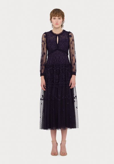 Vestido de encaje de manga larga en un tono púrpura oscuro con bordados florales, falda de tul en capas y detalle de escote en forma de lágrima. Acentuado con tejido transparente.