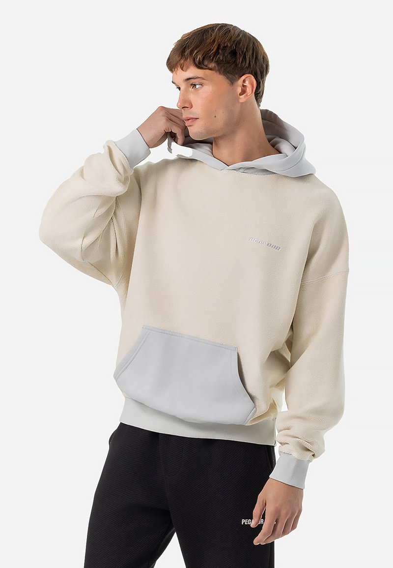 Beige fleecetrui met een grijze capuchon en zak, voorzien van geribbelde boorden en een klein logo op de borst. Zachte textuur en een losse pasvorm.