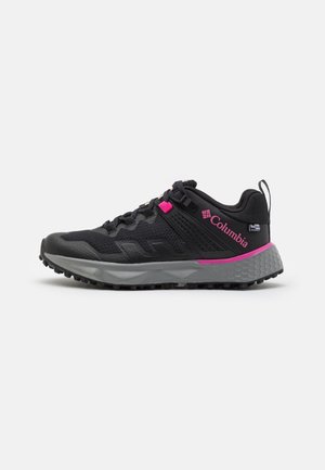 Zapatillas deportivas negras con parte superior texturizada, acentos rosas y suela gris. Cuentan con un tirador y un sistema de cordones seguro.