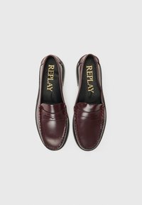 Mocasini din piele burgundy, tip slip-on, cu cusături detaliate și un design structurat. Au talpă din cauciuc negru și o branț branduit.