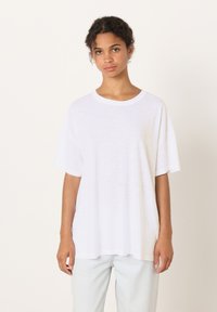 T-shirt bianca oversize con scollo rotondo e maniche corte. Realizzata in un tessuto leggero e leggermente strutturato. Senza motivi o dettagli visibili.