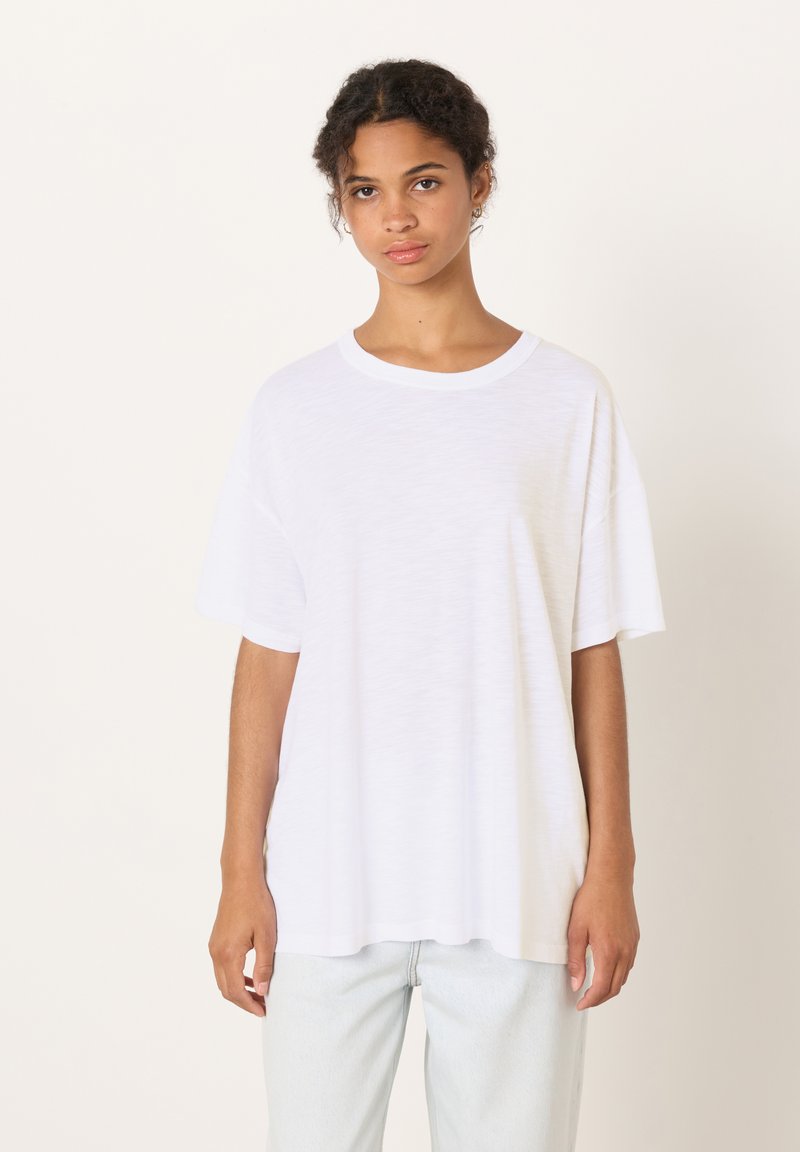 T-shirt bianca oversize con scollo rotondo e maniche corte. Realizzata in un tessuto leggero e leggermente strutturato. Senza motivi o dettagli visibili.
