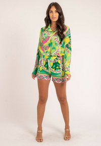 Ensemble coloré en deux pièces composé d'une chemise à manches longues et d'un short vert, rose et jaune, avec des motifs floraux abstraits et des détails de bordure.